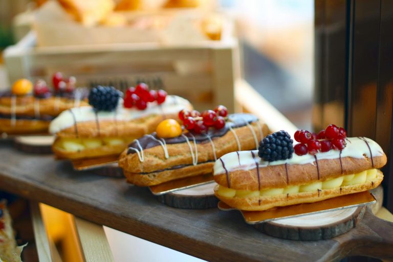 Delicious eclairs topped with fresh berries and custard filling on display.