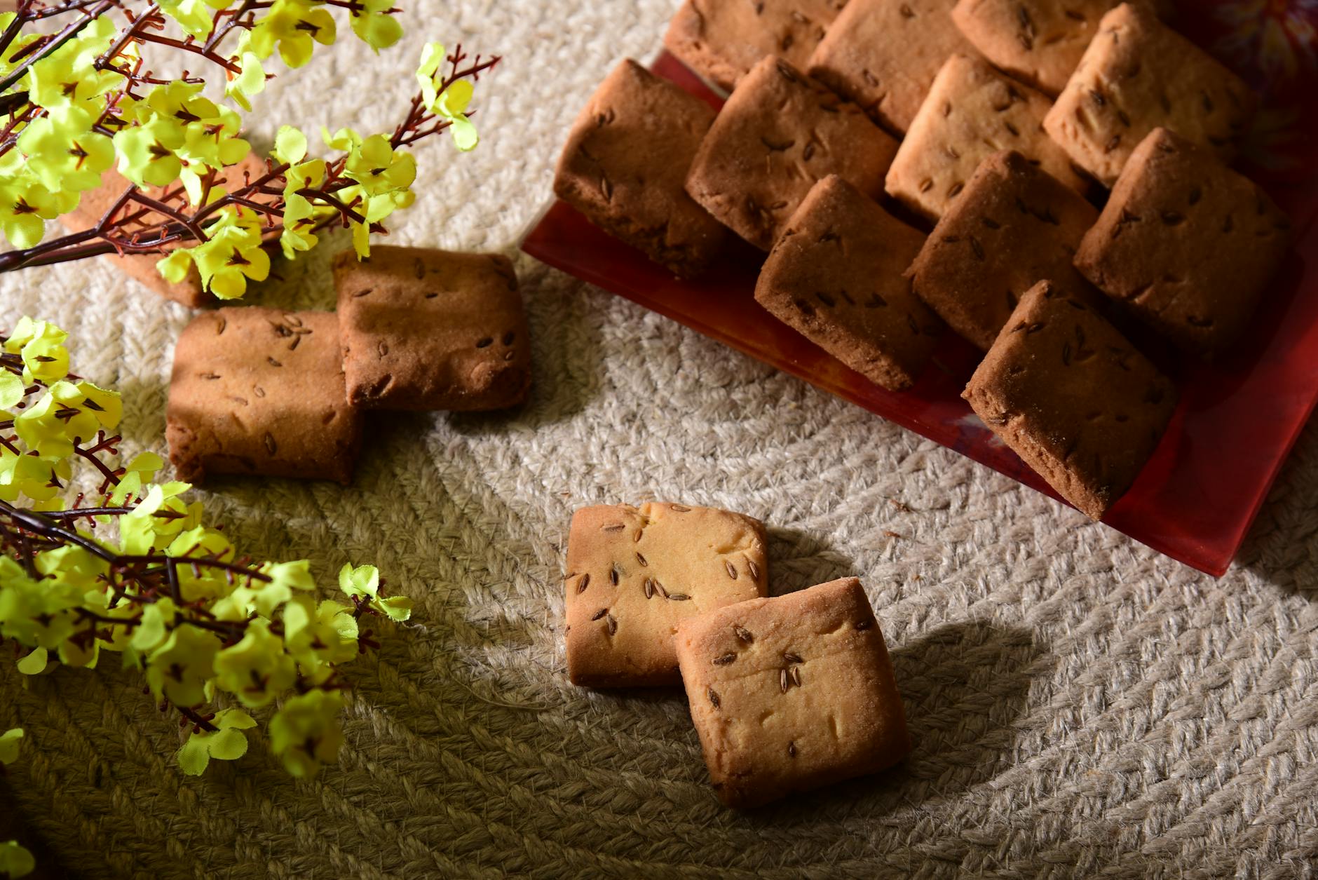 Freshly baked homemade Shakkarpara cookies on a woven mat with yellow flowers, perfect for a sweet treat.