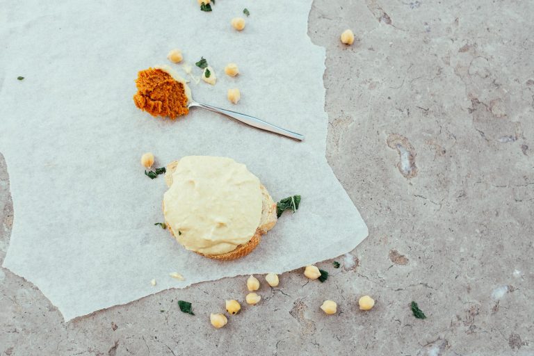 Delicious chickpea bread slice with spices and garnish on parchment paper, photographed top view.