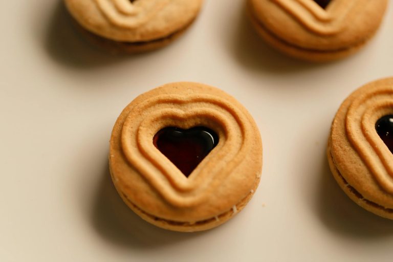 Delicious heart-shaped jam-filled biscuits arranged on a light surface.