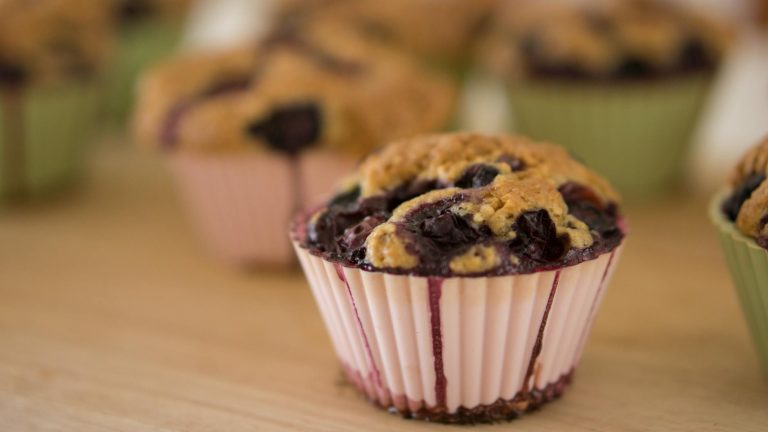 Delicious homemade blueberry muffins in colorful molds on a wooden table.