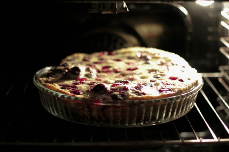 A freshly baked cherry clafoutis in a glass dish inside an oven, capturing the essence of homemade desserts.