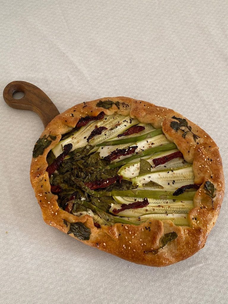 A mouthwatering homemade vegetable galette topped with zucchini and greens, perfect for a fresh meal.