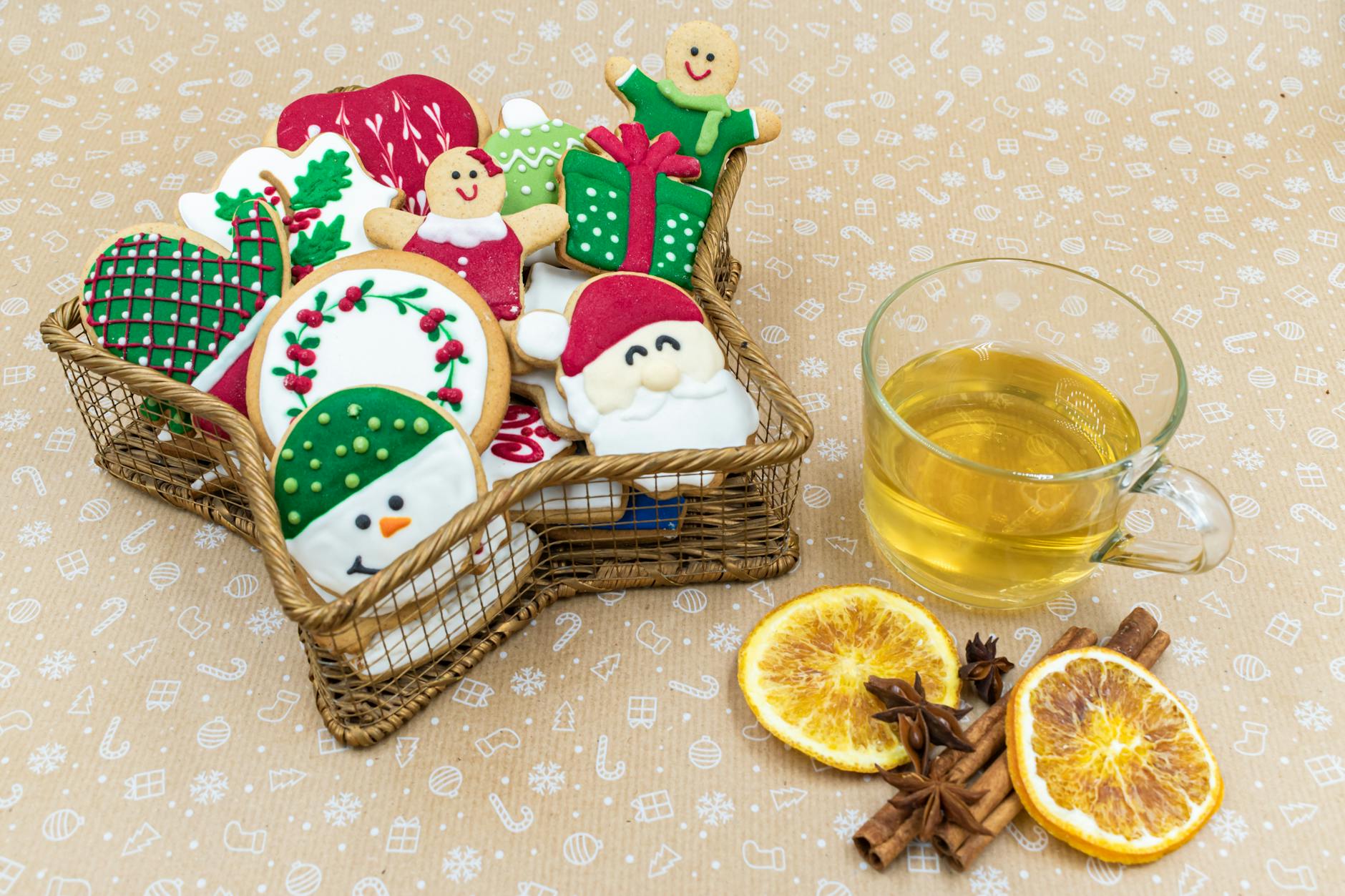 Festive cookies in a basket with a cup of tea, oranges, and spices. Perfect for holiday celebrations.