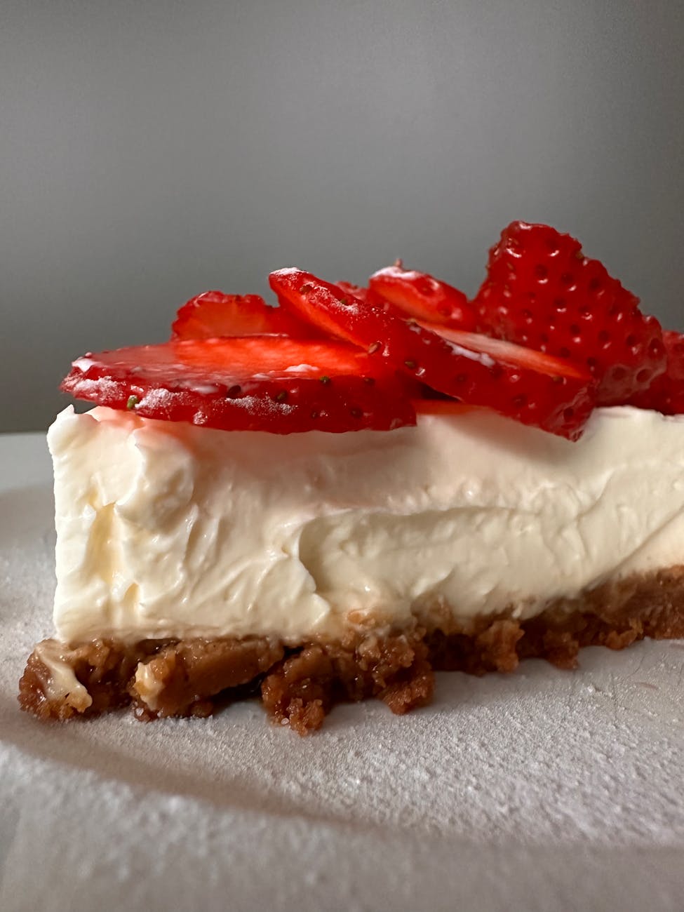 Delicious cheesecake slice with strawberries on crumb base.
