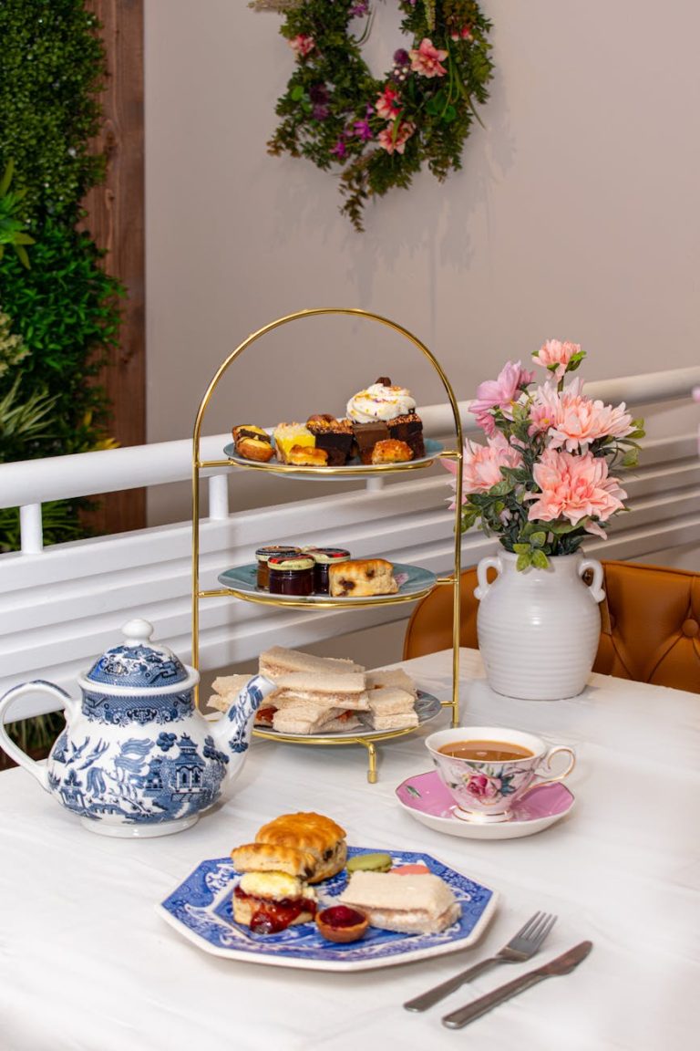 Sophisticated afternoon tea setup with porcelain tea set and floral centerpiece on table.