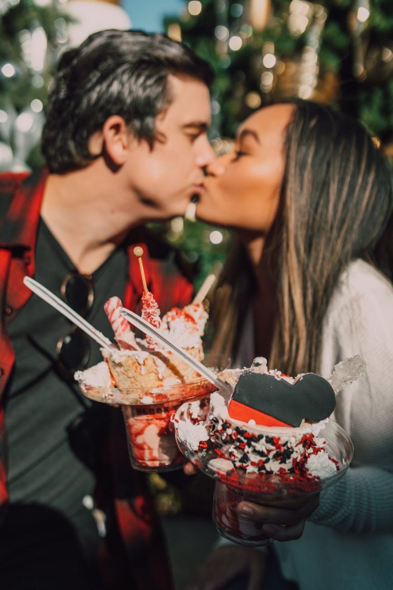 A couple sharing a kiss while holding deliciously decorated desserts, creating a romantic and sweet moment.