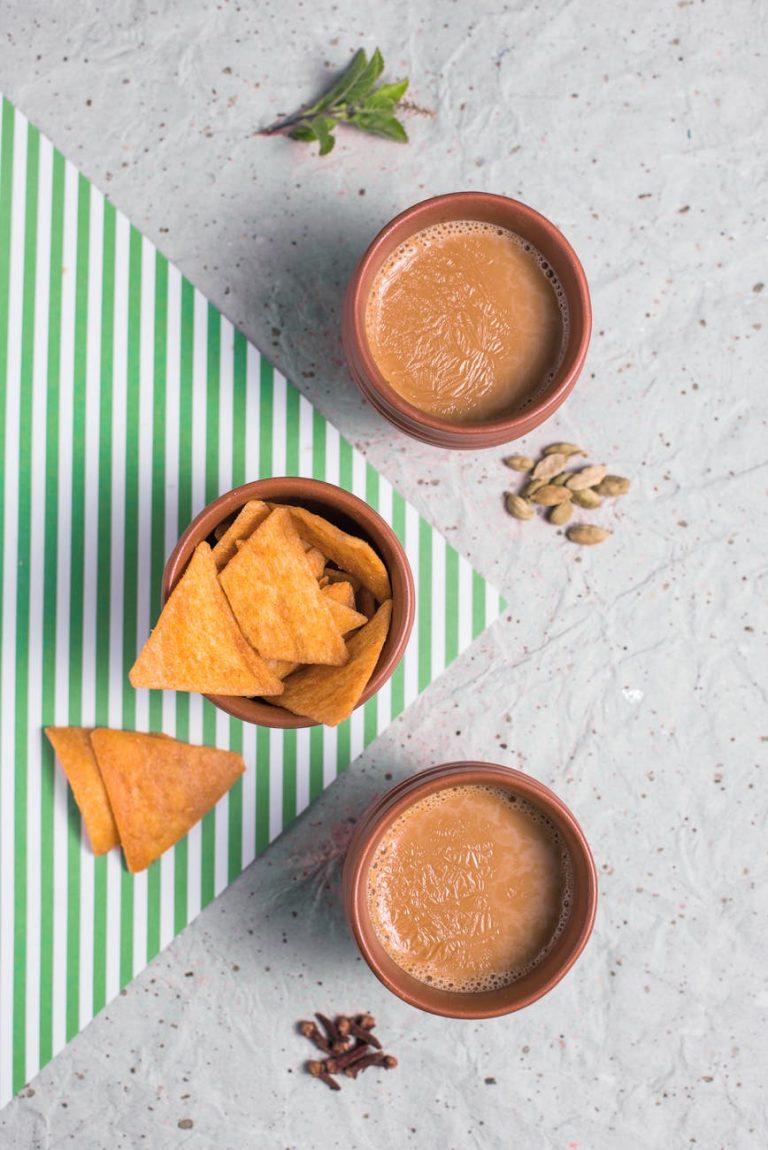 Top view of traditional Indian chai tea with nachos on a striped mat.