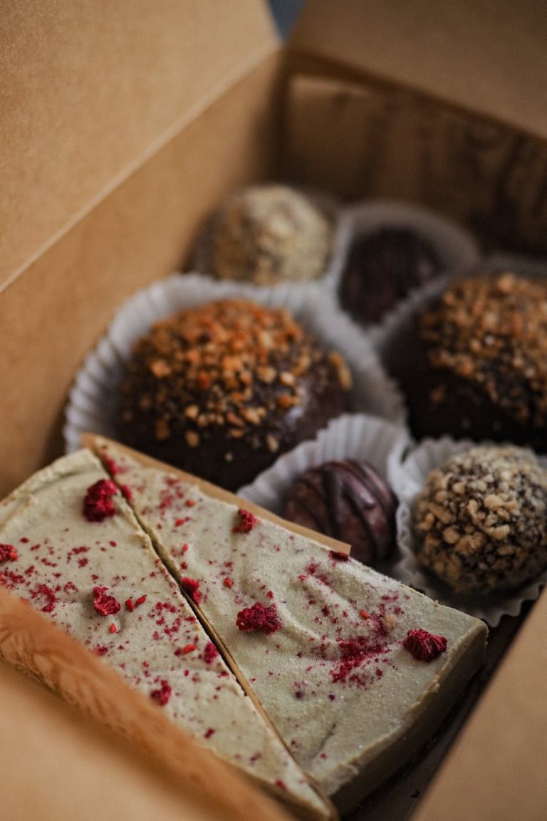 Close-up of assorted truffles and dessert slices in a cardboard box, perfect for gift-giving.