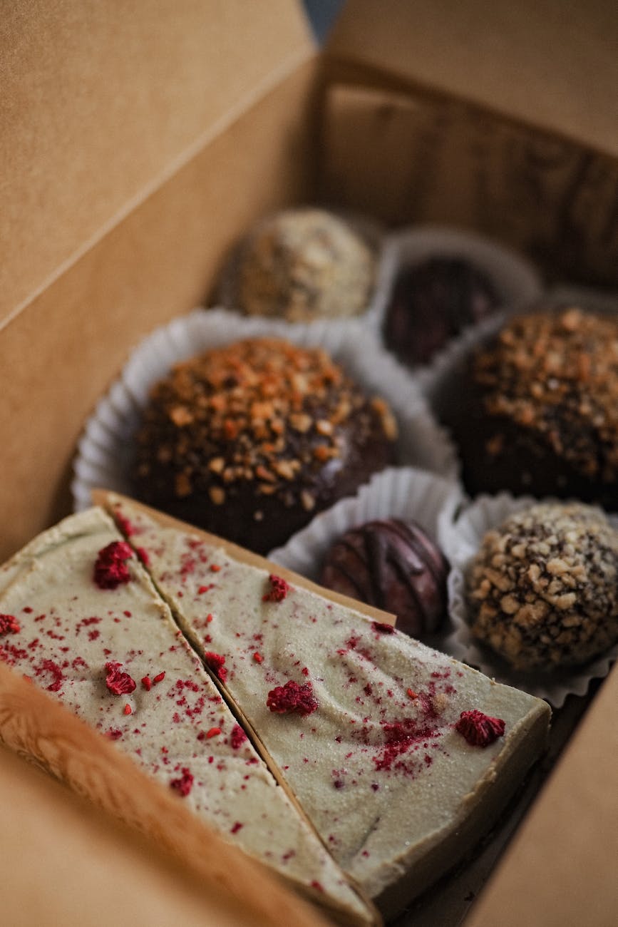Close-up of assorted truffles and dessert slices in a cardboard box, perfect for gift-giving.