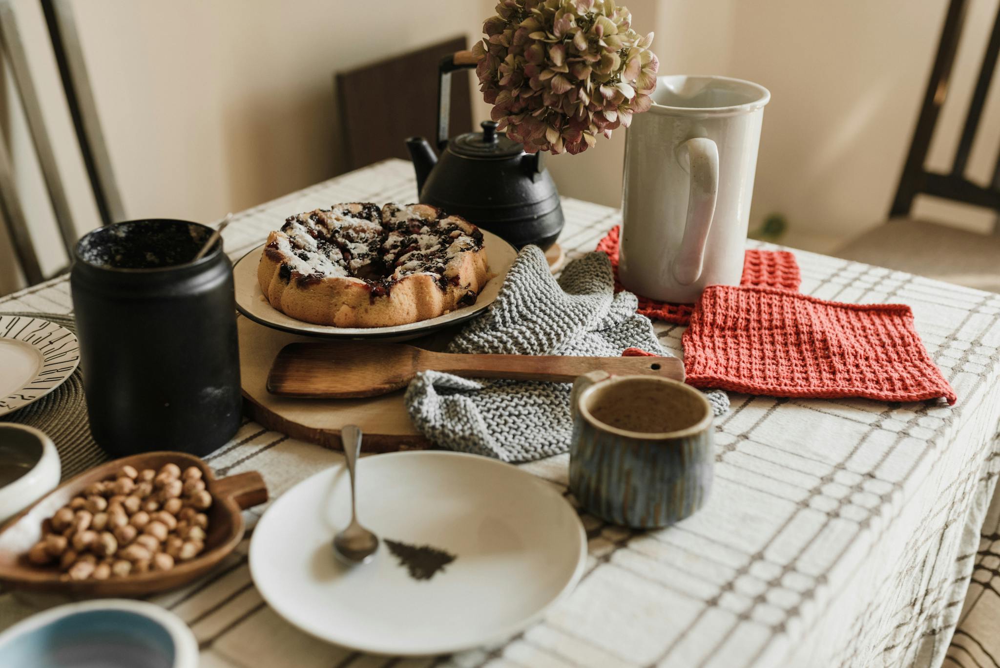 Inviting breakfast scene with a homemade cake, coffee, and cozy textiles on a kitchen table.