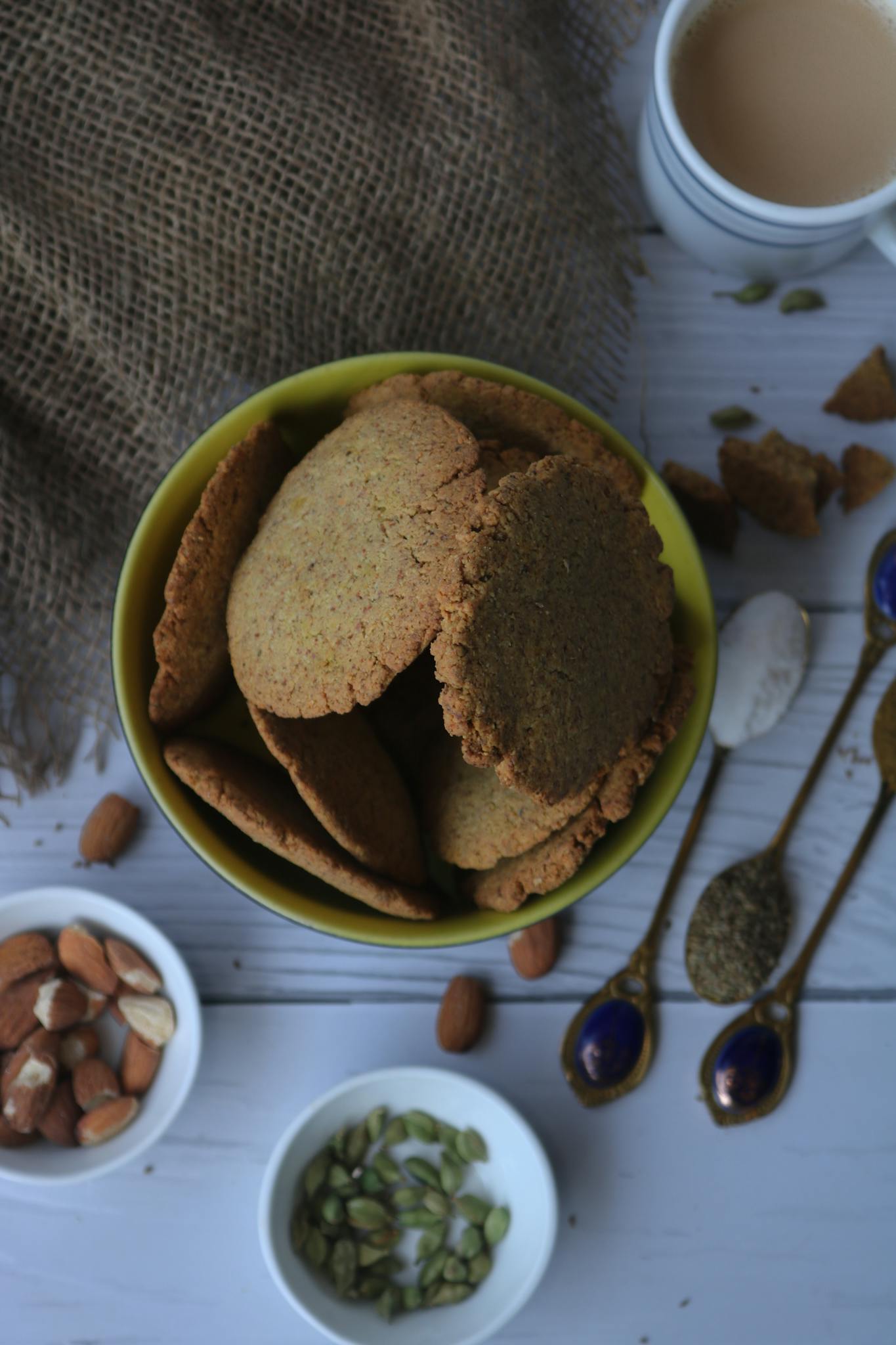 Top view of cookies with nuts and tea on rustic fabric, perfect for culinary themes.