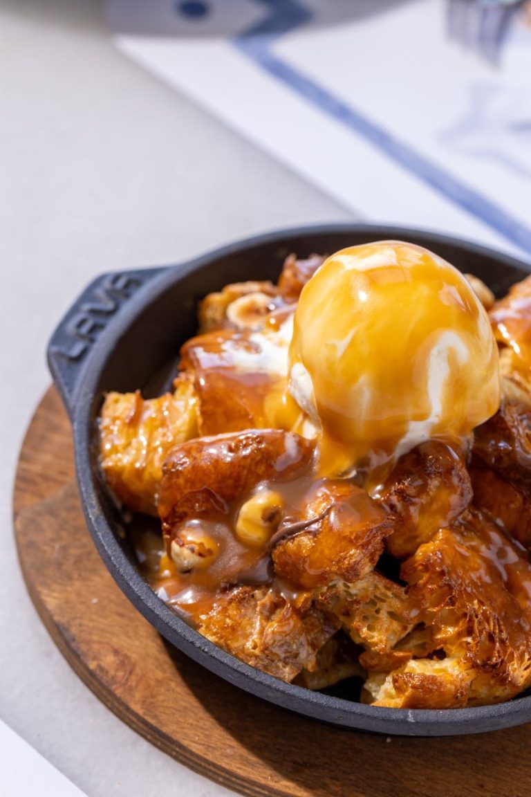 Indulgent caramel bread pudding topped with ice cream in a skillet.